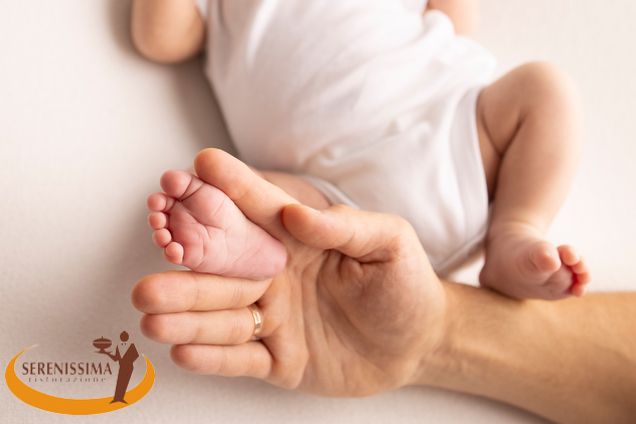 Adult hand holding newborn baby's foot